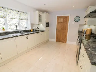 a kitchen with white cabinets and a sink and a window at Ty Ni in Dyffryn