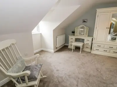 a bedroom with a chair and a vanity and a mirror at Ty Ni in Dyffryn