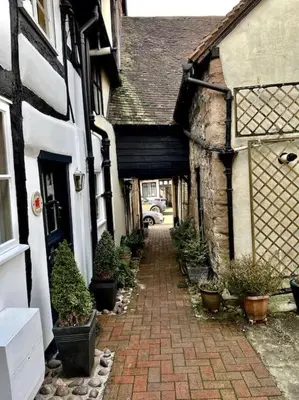 an alley in an old building with potted plants at Hideaway Cottage in Ludlow
