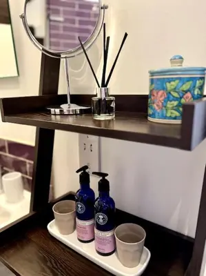 a shelf with two bottles of soap and cups at Hideaway Cottage in Ludlow