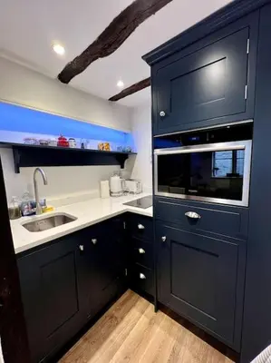 a blue kitchen with a sink and a microwave at Hideaway Cottage in Ludlow
