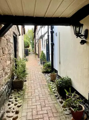 an alley with potted plants on the side of a building at Hideaway Cottage in Ludlow