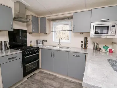 a kitchen with white cabinets and a sink and a stove at The Hideout in Llanina