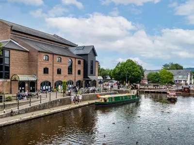 a green boat in a river next to a building at 2 Bed in Brecon oc-51153 in Llandefalle