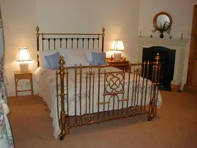 a bed in a bedroom with two lamps and a fireplace at The Coach House at Bryngwyn Hall in Llanfyllin