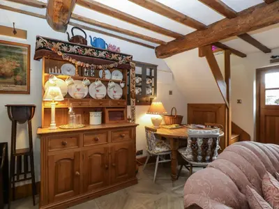 a bedroom with a wooden hutch and a dining room table at Hoarders Cottage in Hereford