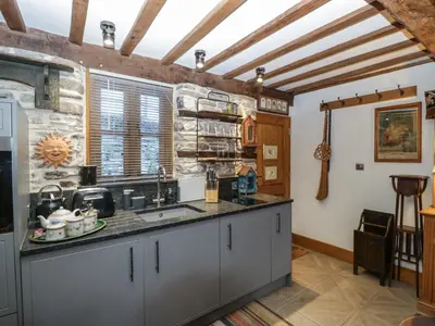 a kitchen with gray cabinets and a stone wall at Hoarders Cottage in Hereford