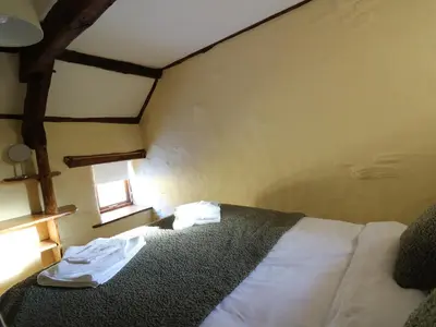 a bedroom with a bed with white sheets and a window at Y Cartws in Llanybydder
