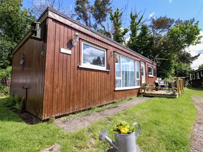 a small wooden cabin with a window in a yard at Chalet Forte in Aberdyfi