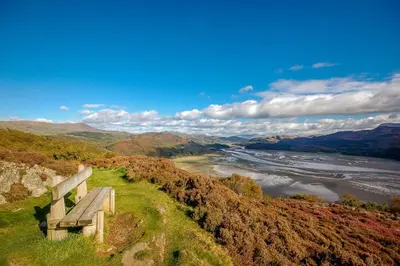a bench sitting on top of a hill overlooking a river at Ty-Gwair-Byrdir in Dyffryn