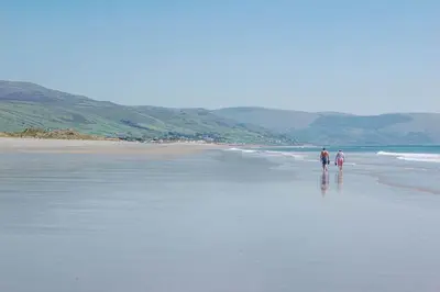 two people walking on a beach near the ocean at Ty-Gwair-Byrdir in Dyffryn