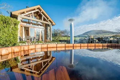 a house on a lake with a reflection in the water at Nant in Dyffryn