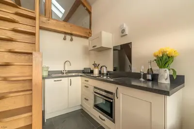 a kitchen with white cabinets and a black counter top at Nant in Dyffryn