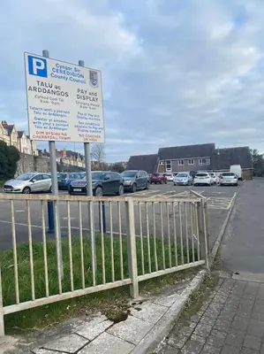 a parking lot with a sign next to a fence at Maisonette flat Aberystwyth in Aberystwyth