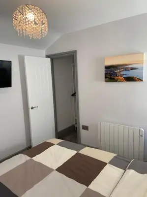 a bedroom with a bed and a chandelier at Maisonette flat Aberystwyth in Aberystwyth