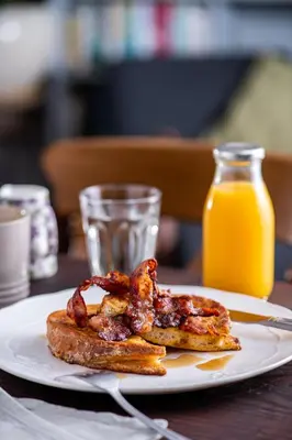 a plate with two pieces of bacon and a glass of orange juice at The Cedars in Builth Wells