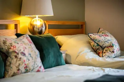 a bedroom with a bed with pillows and a lamp at The Cedars in Builth Wells