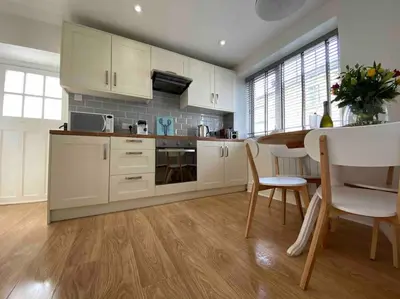 a kitchen with white cabinets and a table and chairs at Cosy Cottage in Aberaeron