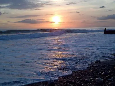 a sunset on a beach with the ocean at Beach Front Apartment in Tywyn in Tywyn