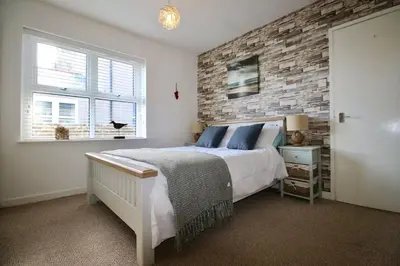 a bedroom with a bed and a brick wall at Beach Front Apartment in Tywyn in Tywyn