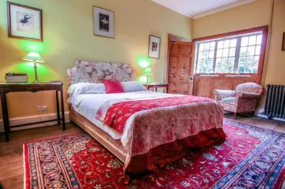 a bedroom with a large bed and a red rug at Garden House in North Lydbury