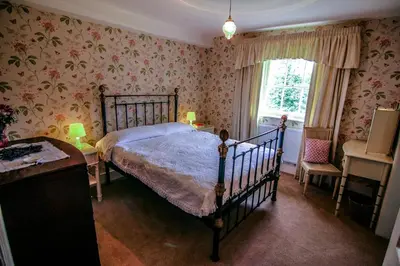 a bedroom with a bed and floral wallpaper at Garden House in North Lydbury