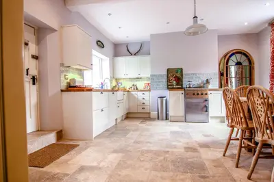 a kitchen with white cabinets and a table and chairs at Garden House in North Lydbury