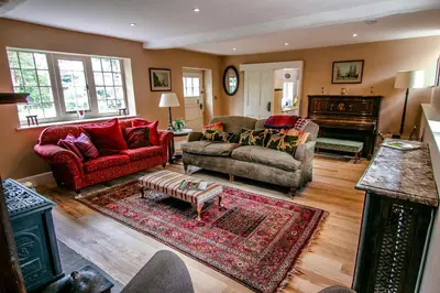 a living room with two couches and a piano at Garden House in North Lydbury