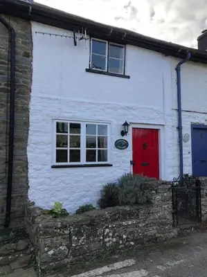 a white house with a red door and windows at Lavender Cottage, 3 School Road, Clun, Shropshire in Clun