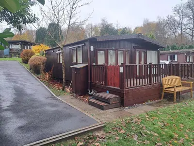 a small cabin with a bench on the side of a driveway at Bunny Lodge 30 - Riverside in Builth Wells