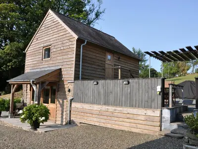 a large wooden barn with a fence in front of it at Rockhill Farm Hay Barn in Craven Arms