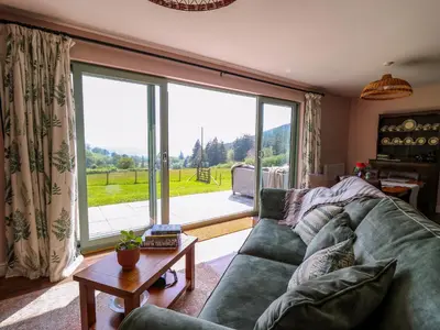 a living room with a couch and a large window at Dol Blodau in Llandrindod Wells