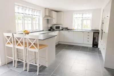 a kitchen with white cabinets and a island with stools at Afonfa - Llanuwchllyn in Bala
