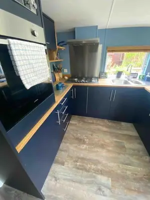 a kitchen with blue cabinets and a sink at The Cherries - Caer beris holiday park 2 bedroom lodge - No commercial vehicles allowed on site in Builth Wells