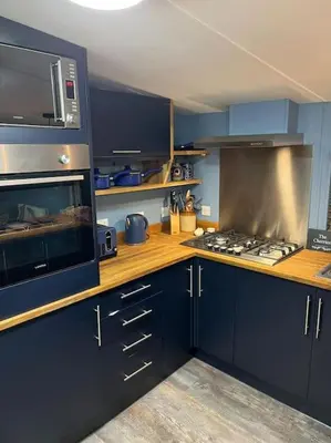 a kitchen with blue cabinets and a stove top oven at The Cherries - Caer beris holiday park 2 bedroom lodge - No commercial vehicles allowed on site in Builth Wells
