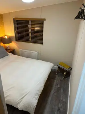 a bedroom with a white bed and a window at The Cherries - Caer beris holiday park 2 bedroom lodge - No commercial vehicles allowed on site in Builth Wells
