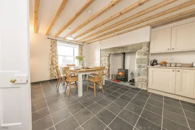 a kitchen and dining room with a table and a fireplace at Ty-Newydd-Frongaled in Dyffryn