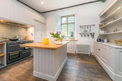 a kitchen with white cabinets and a wooden counter top at Gors-Y-Gedol in Dyffryn