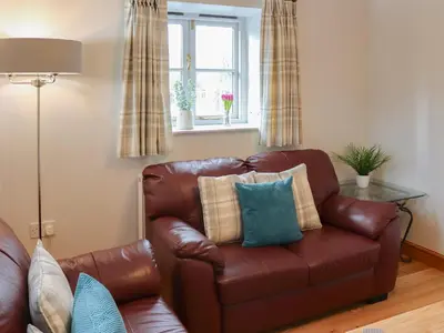 a brown leather couch in a living room with a window at Glanllyn Lodge in Llanuwchllyn