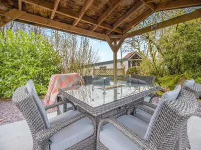 a glass table and chairs on a patio at Frondeg Bach in Cross Inn