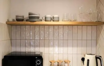 a shelf above a stove in a kitchen with dishes at The Cwtch in Ludlow
