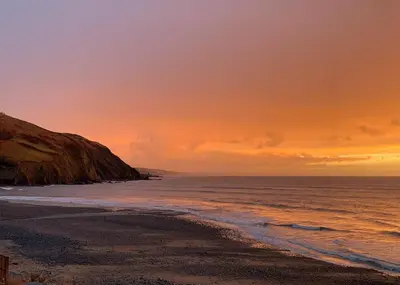 a sunset over a beach with the ocean at Aber Bay Holiday Park in Aberystwyth