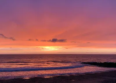 a sunset on the beach with the ocean at Aber Bay Holiday Park in Aberystwyth