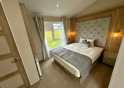 a bedroom with a large bed and a window at Aber Bay Holiday Park in Aberystwyth