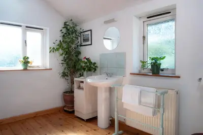 a white bathroom with a sink and a mirror at Yr Hen Efail - Old Smithy in Tregaron