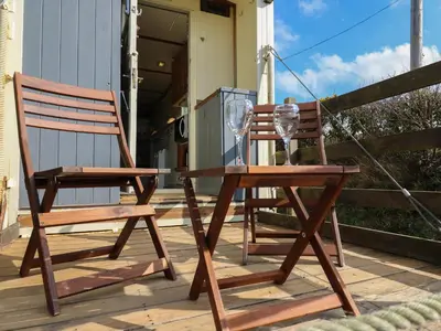 two wooden chairs and a table and a wine glass at Sea the Stars in New Quay