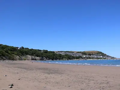 a beach with people walking on the sand and the ocean at Sea the Stars in New Quay