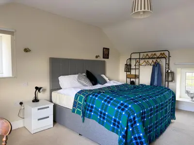 a bedroom with a large bed with a plaid blanket at Crogal Farmhouse in New Quay