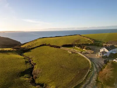 an aerial view of a house on a hill next to the ocean at Crogal Farmhouse in New Quay