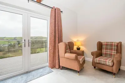 a living room with two chairs and a sliding glass door at Llwynblyfyn in Llandeilo